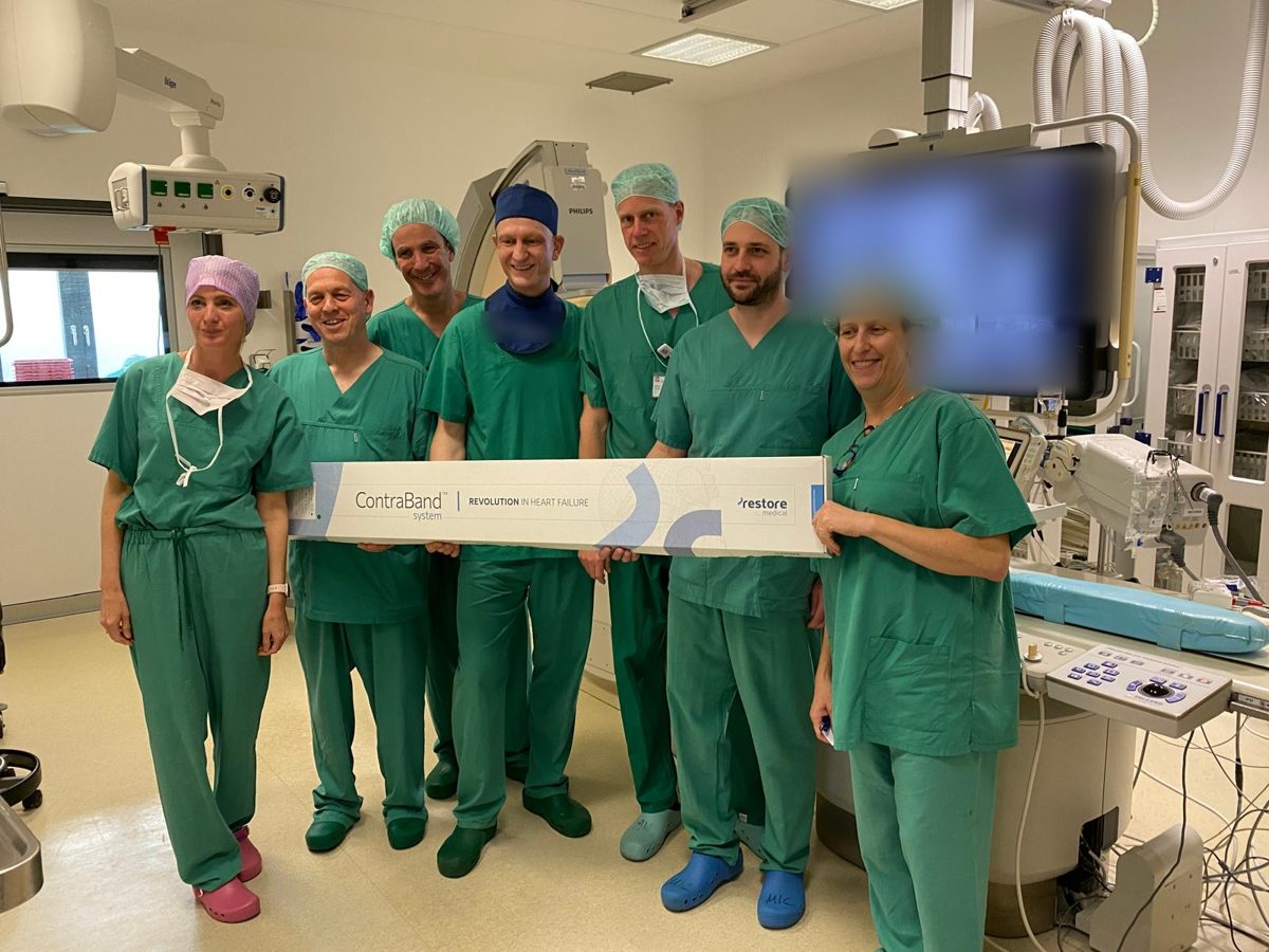 Clinical team in a catheterization lab holding the ContraBand system box
